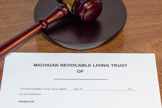 A Michigan Revocable Living Trust laying on a desk with a judges gavel above it symbolizing estate and trust litigation